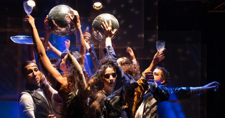 Espetáculo Burburinho onde aparece vários jovens numa roda com braços levantados com copos na mão  